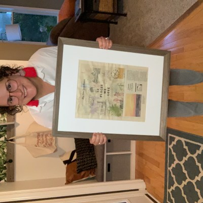 kara holding her framed new york times article and smiling